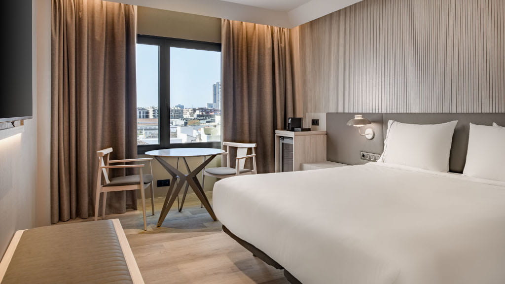 Hotel room with double bed, table, chairs, and window view of Santa Cruz de Tenerife.