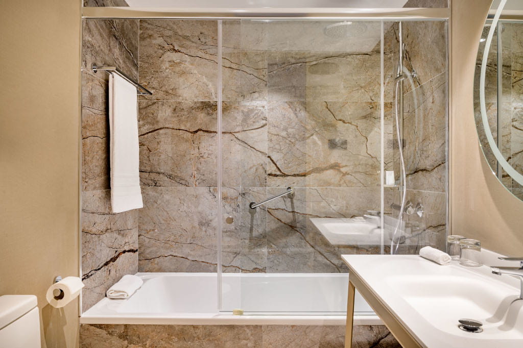 Bathroom with marble walls, bathtub, towel, and sink in Tenerife hotel.