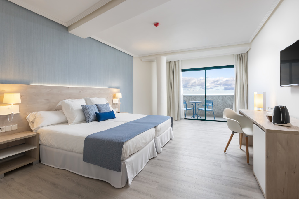 Modern hotel room in Santa Cruz de Tenerife with double bed and ocean view balcony.