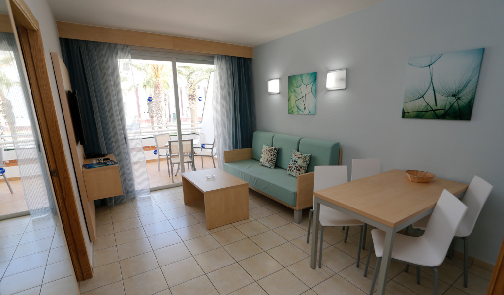 Living room with sofa, dining table, and balcony view at Tenerife hotel.