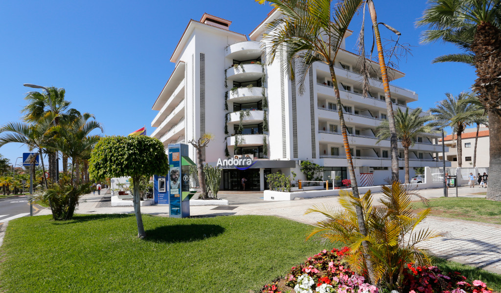 Multi-story hotel and palm trees in Tenerife with sign reading Andorra.
