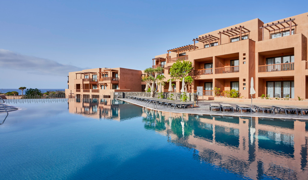 Swimming pool and hotel building in Tenerife with sea views.