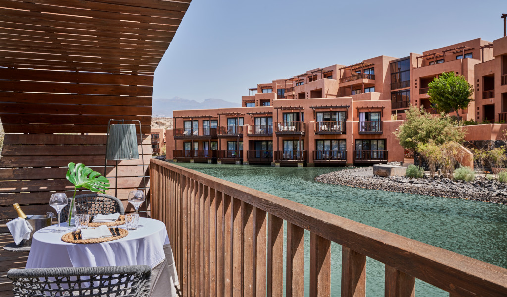 Terrace with table and chairs next to a water canal in a tourist complex in Tenerife.