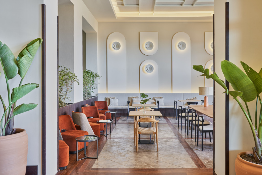 Room with armchairs and tables in a hotel in Tenerife, decorated with plants and wall panels.