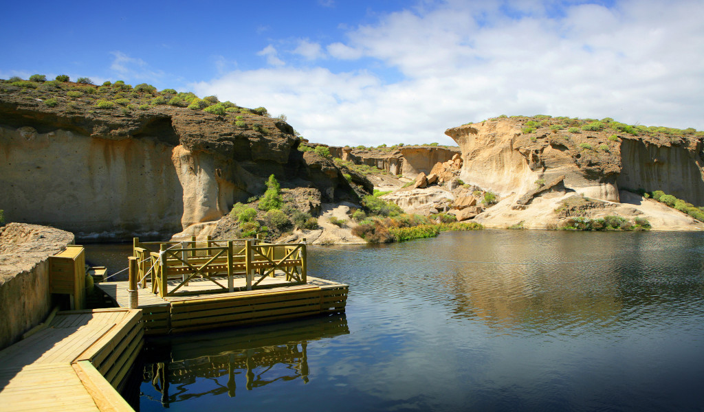 Wooden walkway over a lake with rock formations in Tenerife.