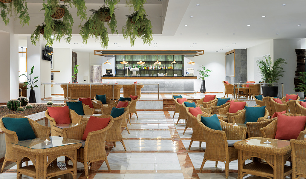 Spacious hotel lounge in Tenerife with wicker chairs and a bar in the background.