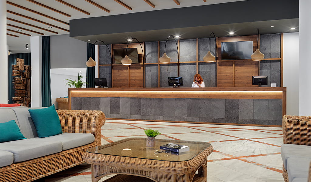 Reception area with wooden desk and computers in a Tenerife hotel lobby.