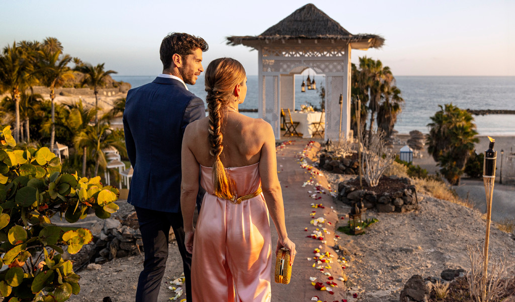 Couple walking towards gazebo at sunset near the ocean in Tenerife.
