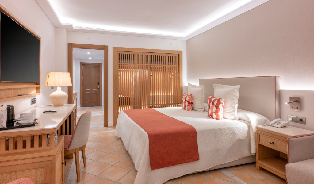 Hotel room in Tenerife with double bed, desk, TV, and warm lighting.
