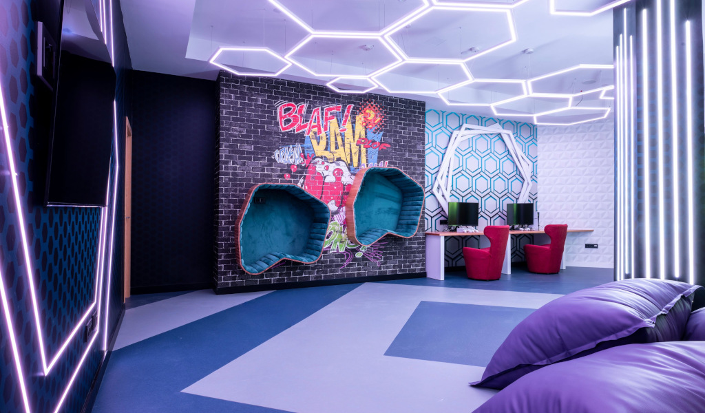 Modern playroom with hexagonal lights, graffiti art, and computers in Tenerife.