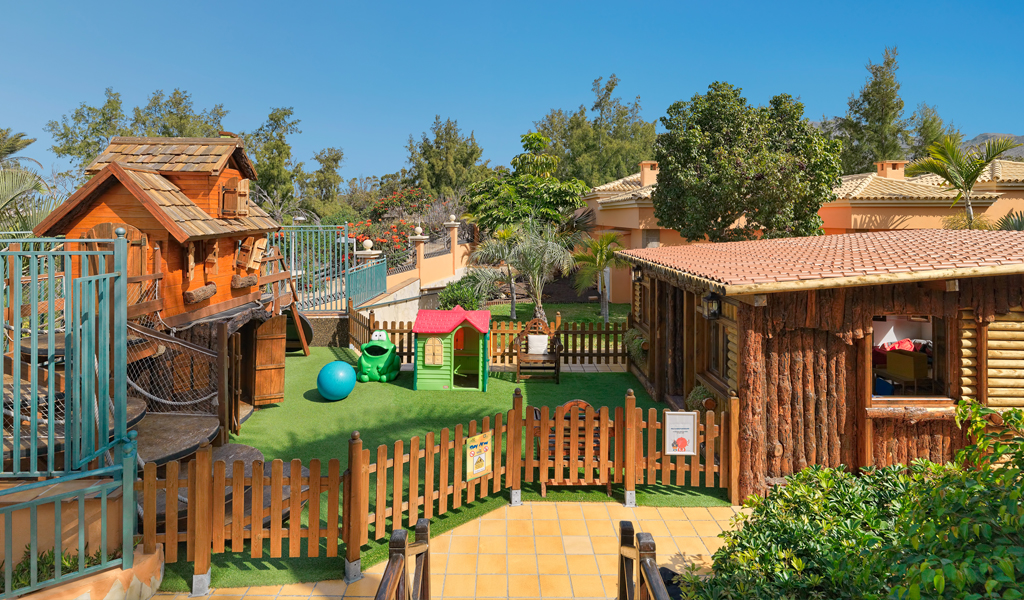 Children's play area with wooden playhouse and green lawn in Tenerife.
