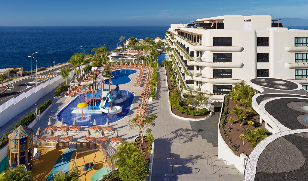 Pool area and playground at a resort in Tenerife with ocean view.