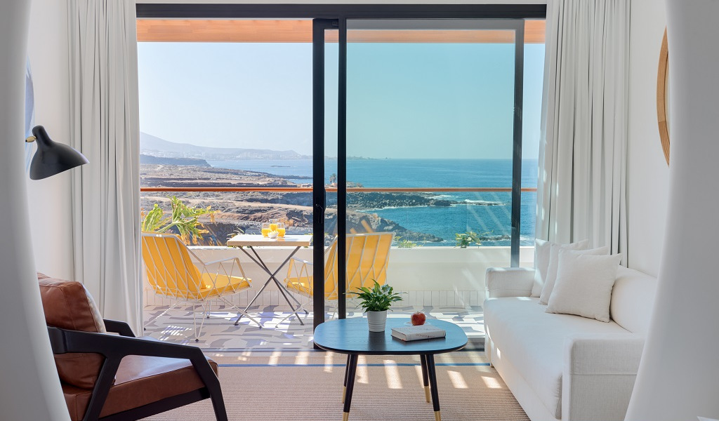 Living room with ocean view through sliding doors, Tenerife coast in background.