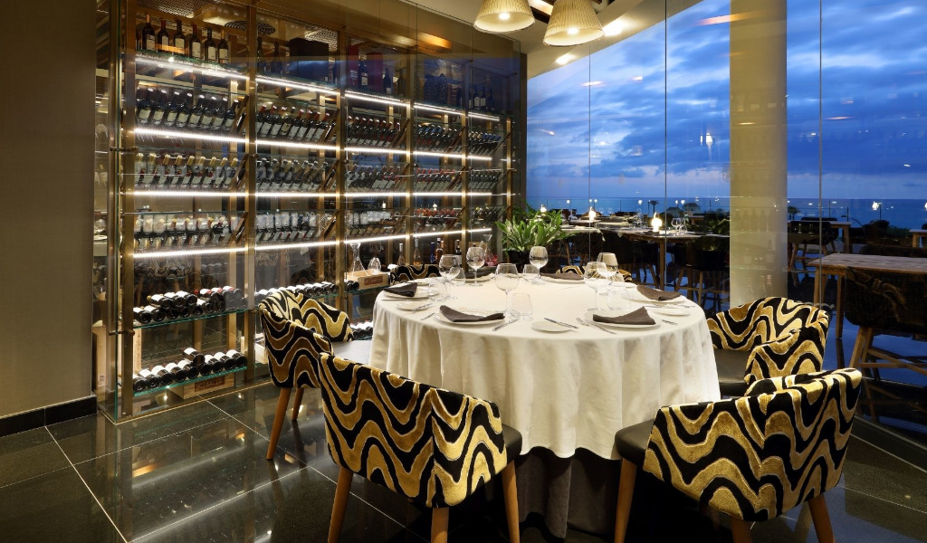 Elegant restaurant table set with wine shelves and ocean view in Tenerife.