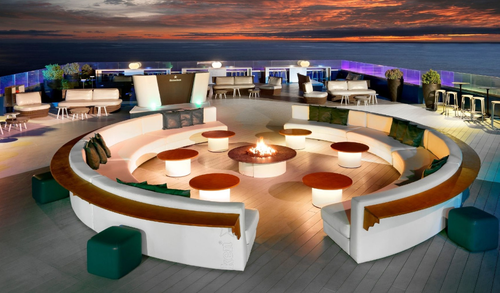 Rooftop lounge with fire pit and ocean view in Tenerife at sunset.