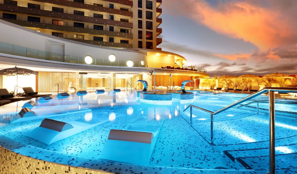 Outdoor pool at a Tenerife hotel with lounge chairs and sunset sky.