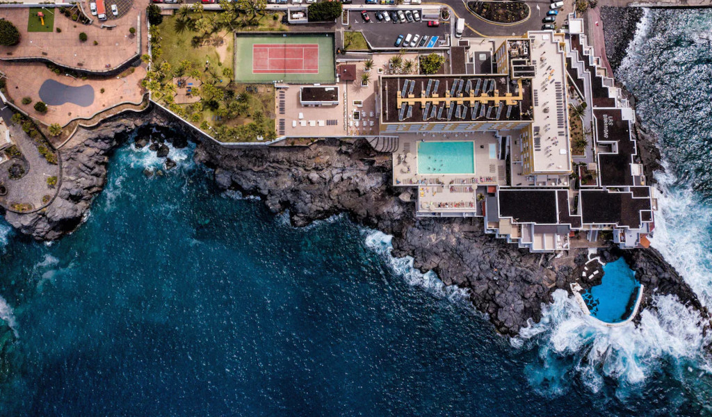 Aerial view of a seaside resort with tennis court and pools in Tenerife.