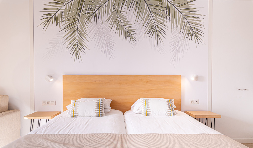 Twin beds with palm leaf decor in a Tenerife hotel room.