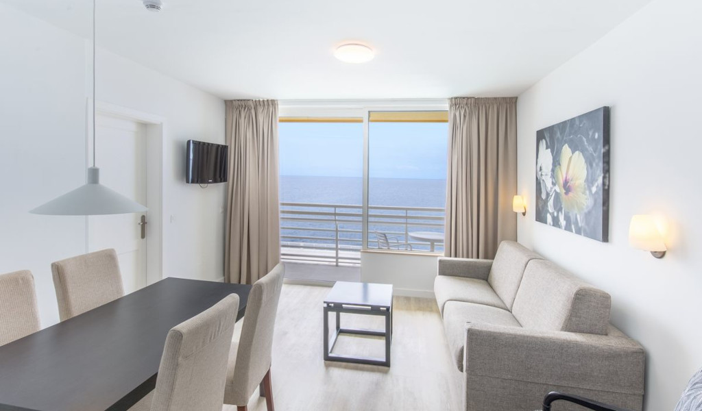 Living room with ocean view, couch, dining table, and TV in Tenerife apartment.