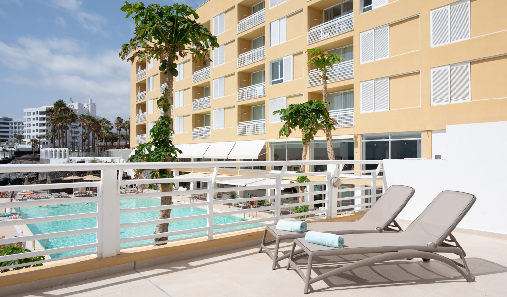 Sun loungers on a terrace overlooking a hotel pool in Tenerife.