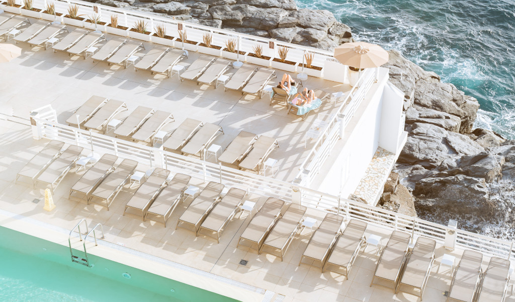 Sunbeds on a terrace by the ocean in Tenerife with two people sunbathing.
