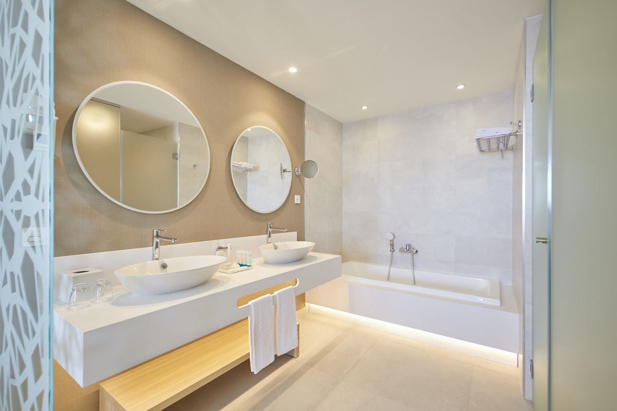 Modern bathroom with two circular mirrors, double sink, and bathtub in Tenerife hotel.