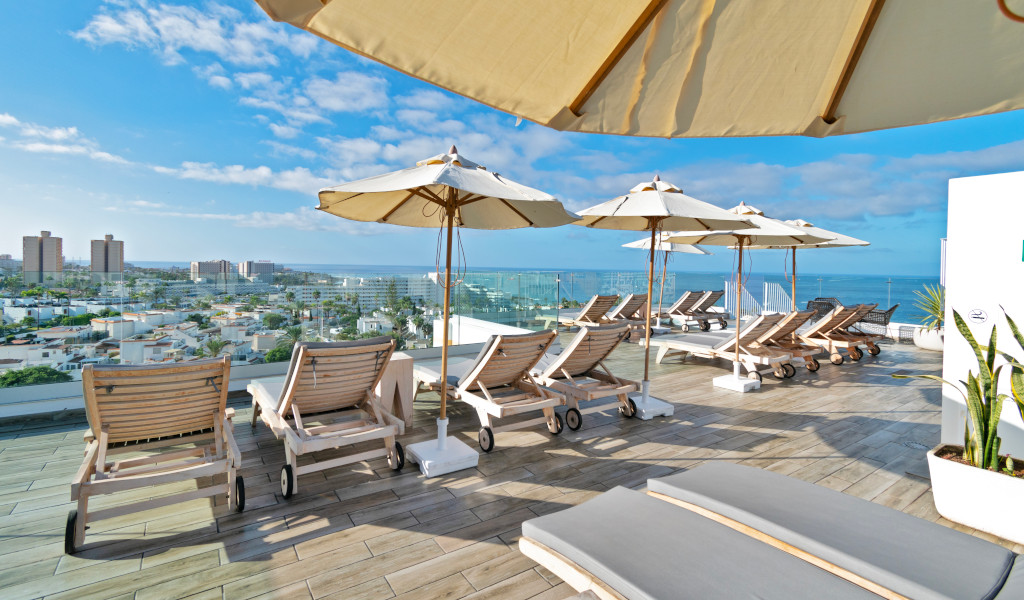 Sun loungers and umbrellas on a rooftop terrace overlooking Los Cristianos, Tenerife.