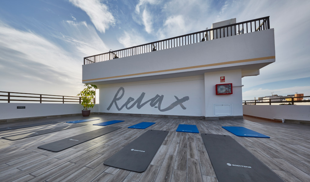 Yoga mats on a rooftop terrace in Tenerife with the word Relax on the wall.
