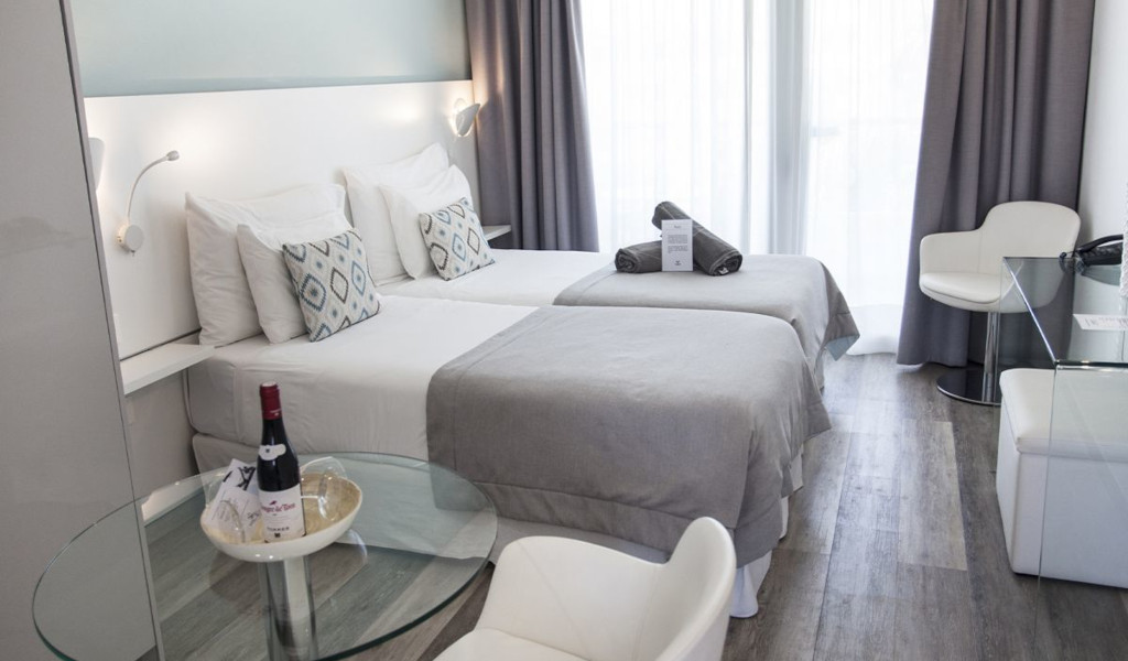 Twin hotel room with grey bedding, wine on table, in Tenerife.