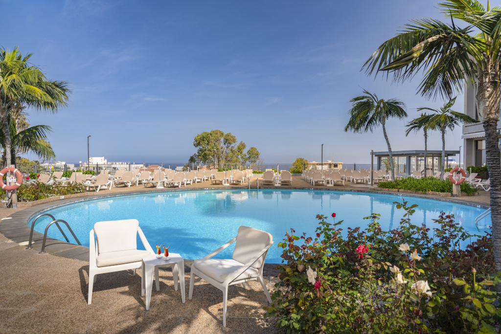 Outdoor swimming pool with palm trees and lounge chairs in Tenerife.