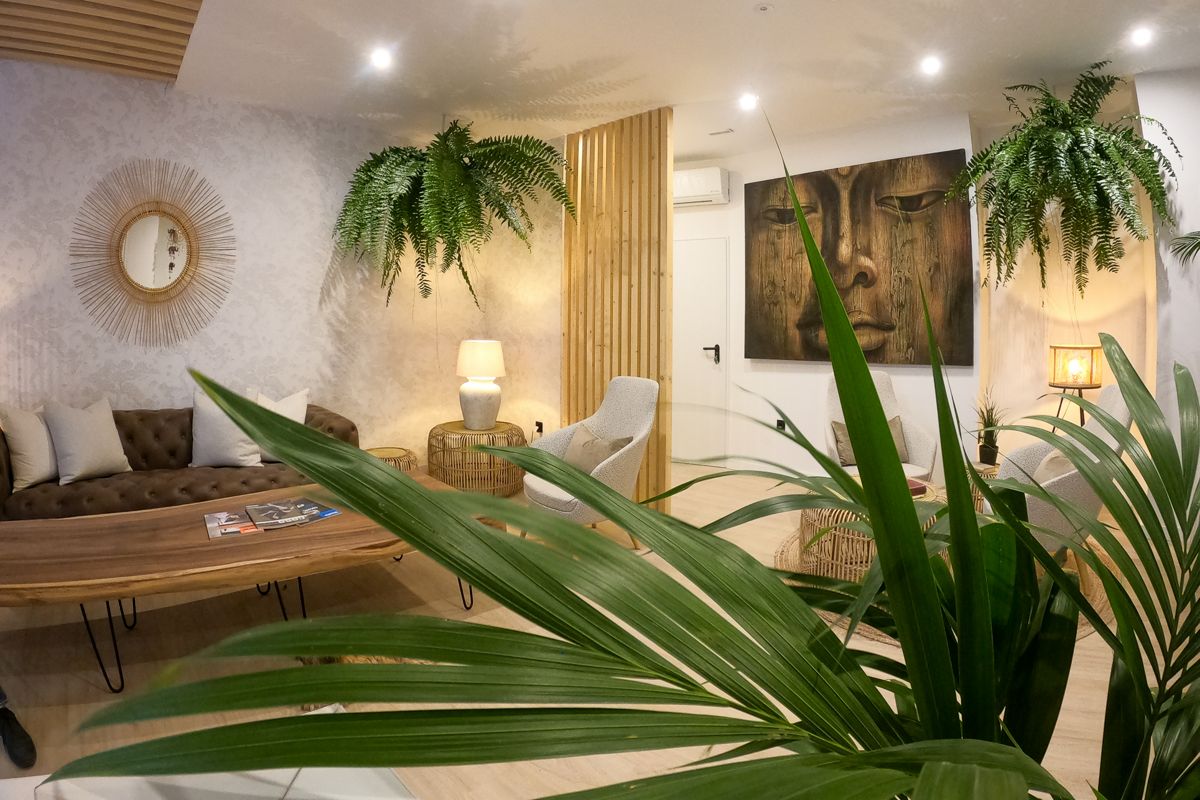 Cozy Tenerife lounge with plants, round mirror, abstract face painting, and soft lighting.