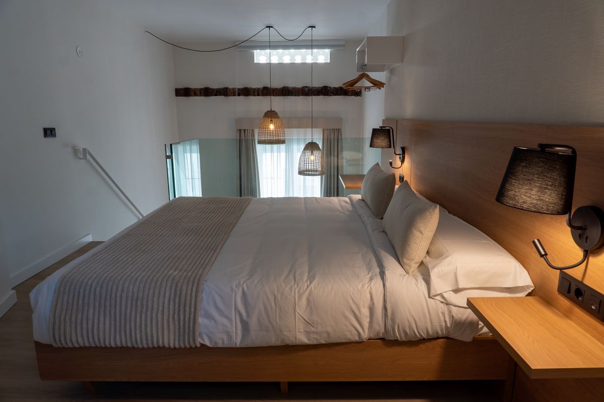 Bed with white sheets, wooden headboard, and woven lamps in Tenerife bedroom.