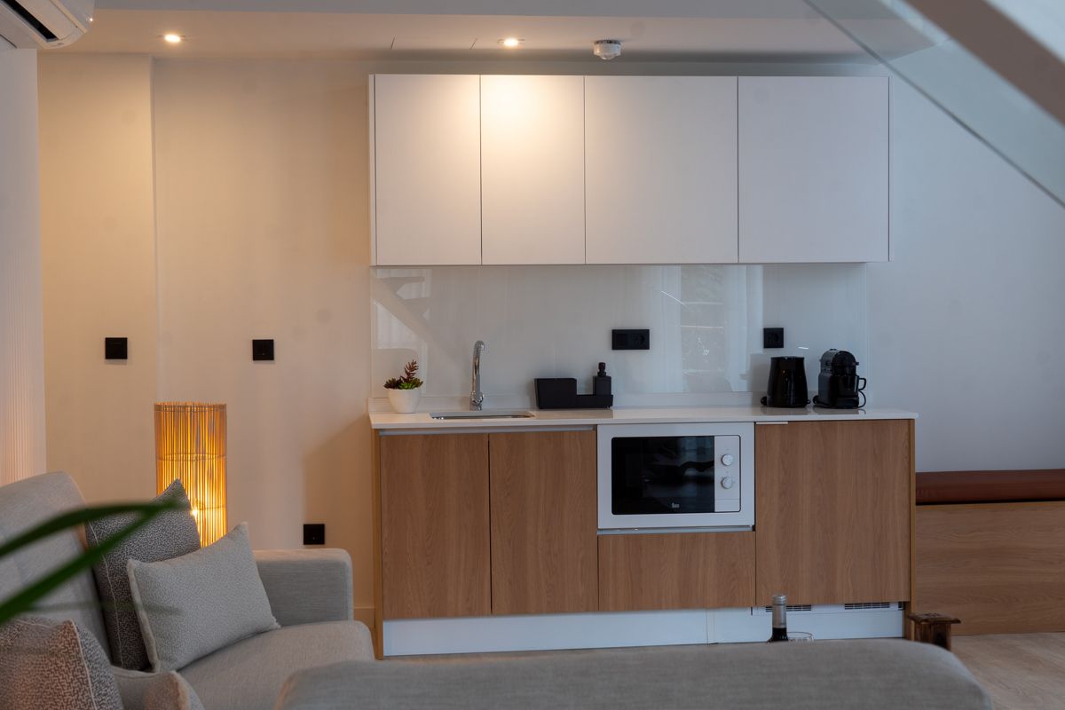 Modern kitchen in Tenerife with white cabinets, wooden lower units, and appliances.
