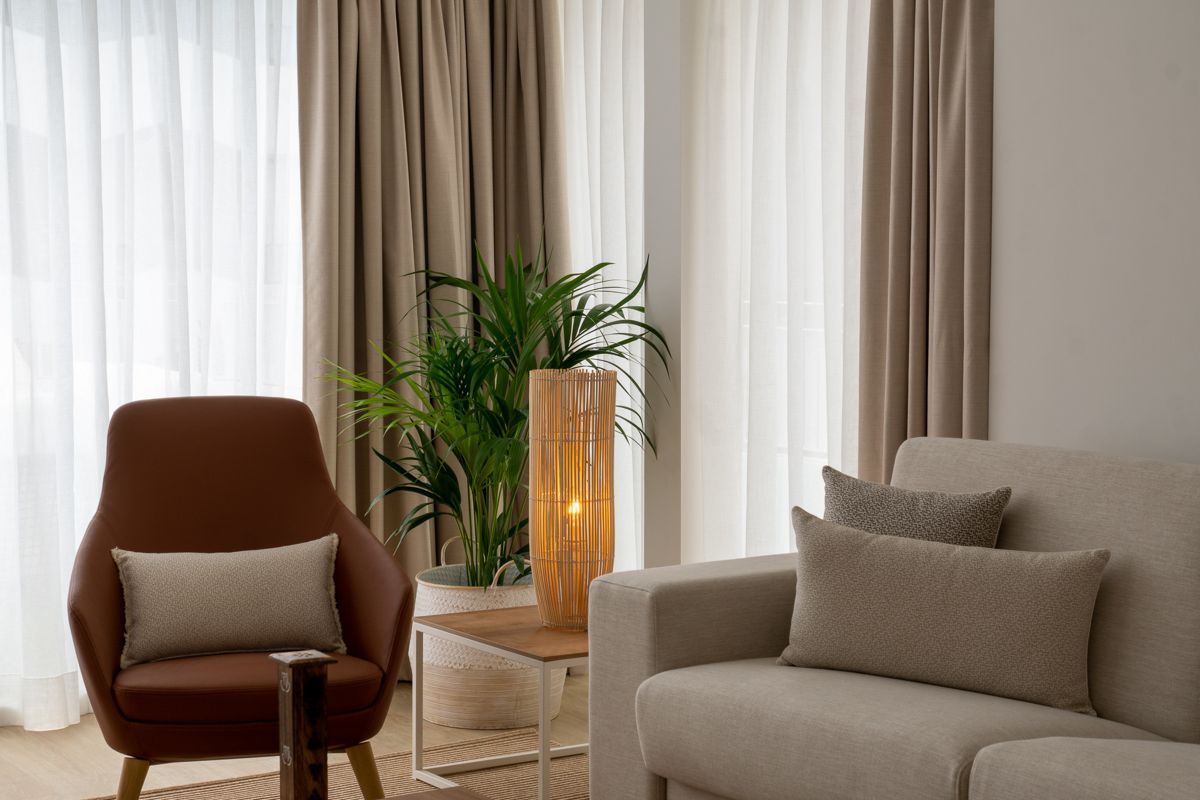 Modern living room with armchair, sofa, cushions, lamp, and plant in Tenerife.