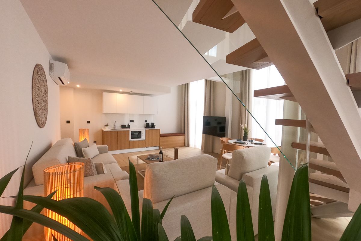 Modern living room in Tenerife with kitchen, staircase, and dining area.