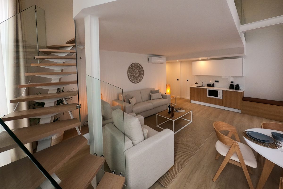 Modern living room and kitchen with staircase in a Tenerife apartment.