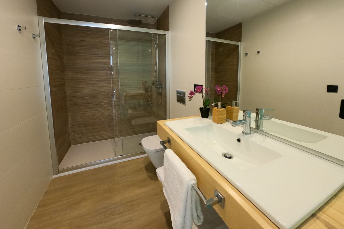 Bathroom with a shower, toilet, sink, and orchids, in Tenerife.