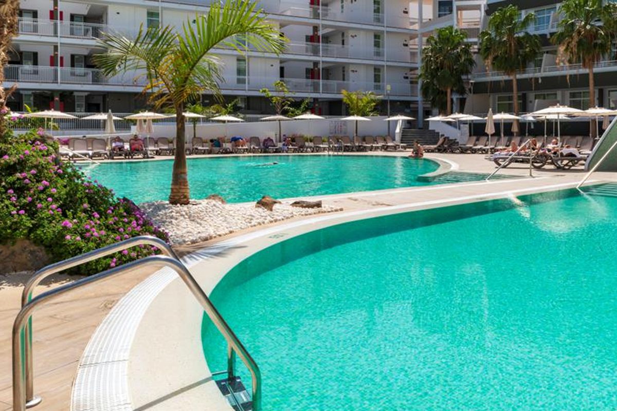 Outdoor pool area with loungers and palm trees at Tenerife hotel.