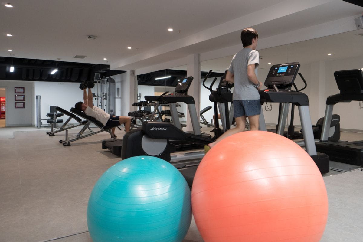 Two people exercising in a gym in Tenerife with treadmills and exercise balls.