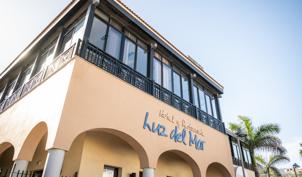 Hotel and Restaurant Luz del Mar building in Tenerife with palm trees nearby.