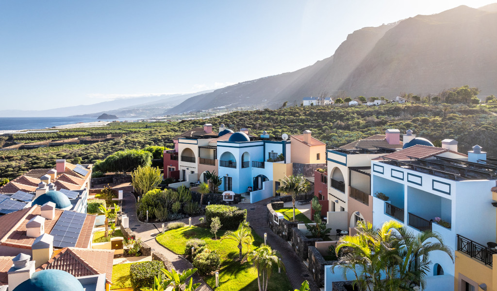 Colorful houses with terraces and gardens in Santiago del Teide, Tenerife, with mountains in the background.