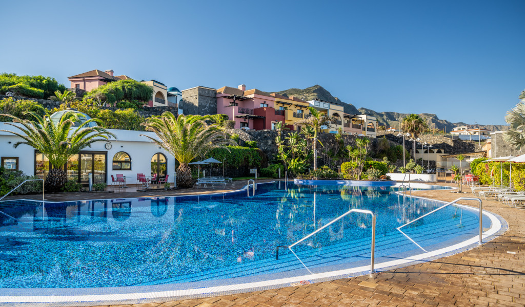 Outdoor pool with palm trees and colorful buildings in Tenerife.