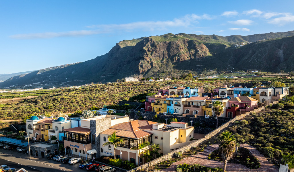 Colorful buildings with mountainous landscape in Tenerife, coastal village setting.