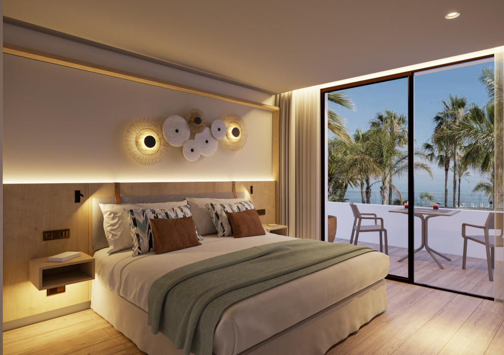 Hotel room with sea view in Tenerife, featuring a cozy bed and balcony with chairs.