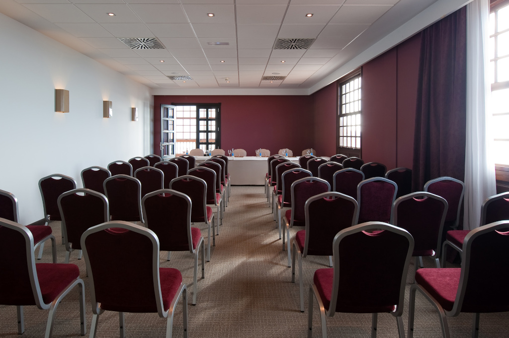 Conference room with rows of red chairs facing a table in Tenerife.
