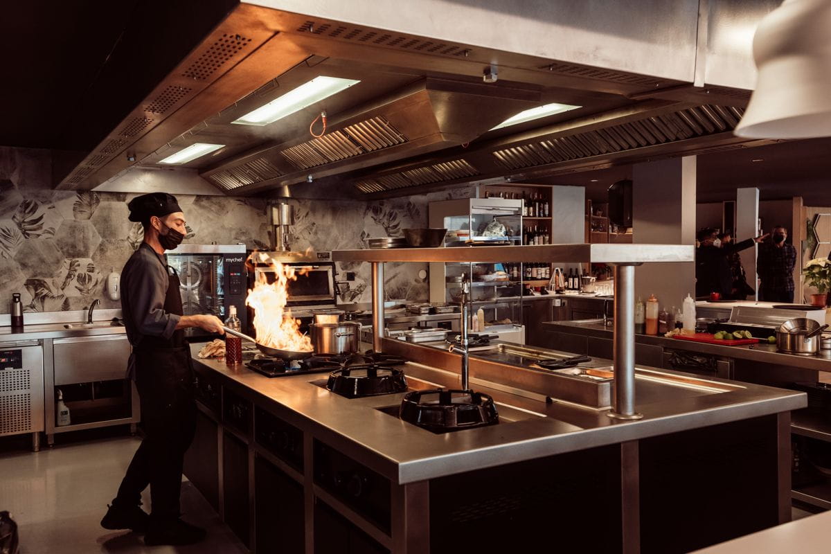 Chef cooking with flames in a professional kitchen in Tenerife.