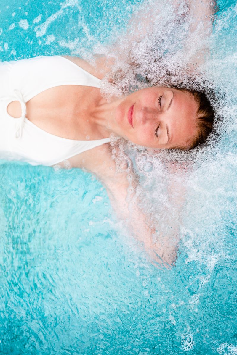 Woman relaxing in turquoise water at a spa in Tenerife.