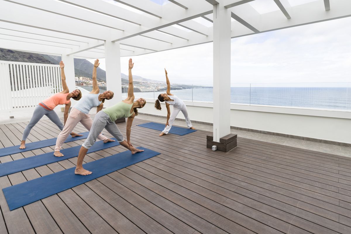 Women practicing yoga on a terrace overlooking the sea in Tenerife.