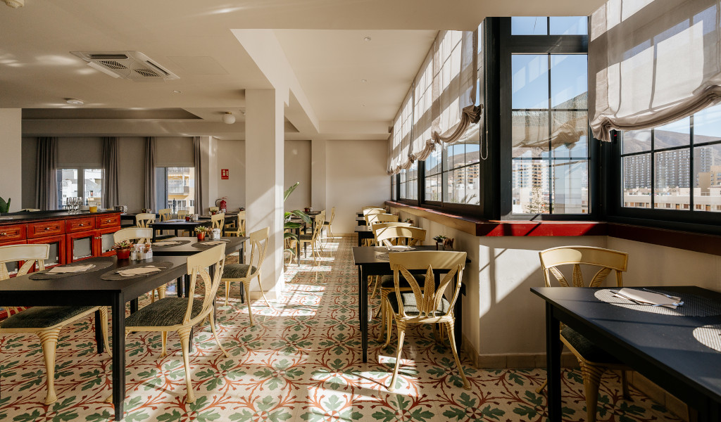 Bright dining area in Tenerife with tables, chairs, and large windows.