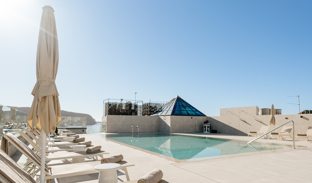 Sun loungers and pool area at Tenerife resort under clear blue sky.